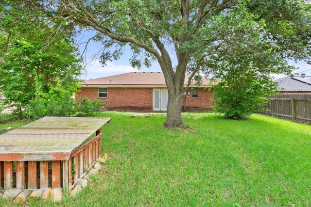 view of yard featuring fence and french doors