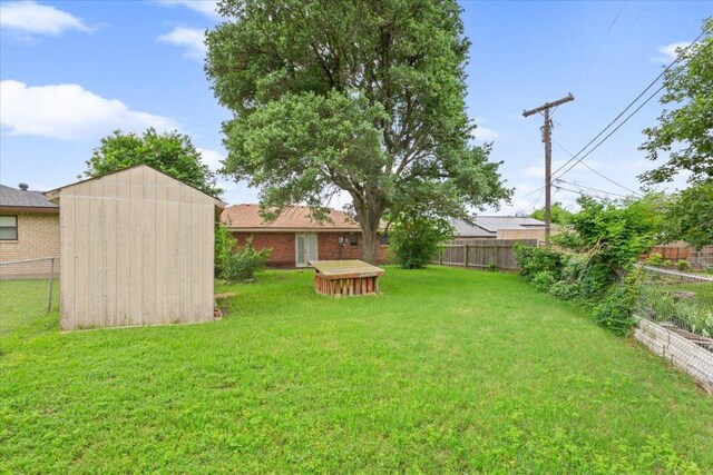 view of yard with a fenced backyard, a shed, and an outbuilding