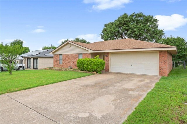 ranch-style home with concrete driveway, brick siding, a front lawn, and a garage