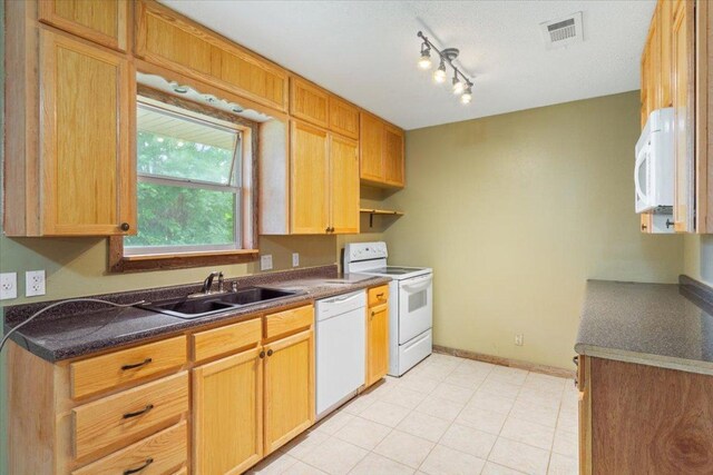 kitchen with visible vents, dark countertops, white appliances, baseboards, and a sink