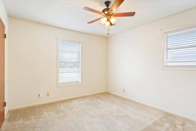 unfurnished room featuring baseboards, ceiling fan, and light colored carpet