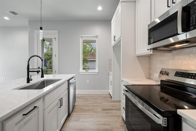 1000B Vargas Rd Unit B, Austin, TX 78741 - kitchen featuring appliances with stainless steel finishes, a sink, light wood-style flooring, tasteful backsplash, and visible vents