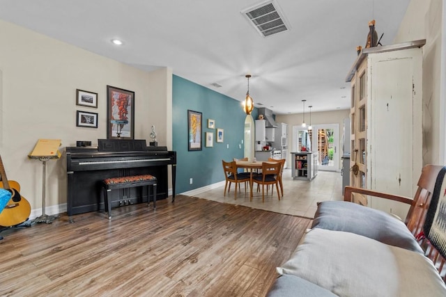 living room with recessed lighting, baseboards, light wood finished floors, and visible vents