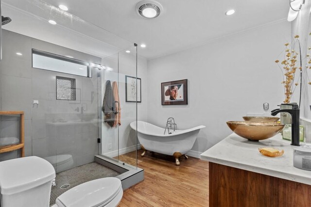full bathroom featuring visible vents, wood finished floors, toilet, a freestanding bath, and a shower stall