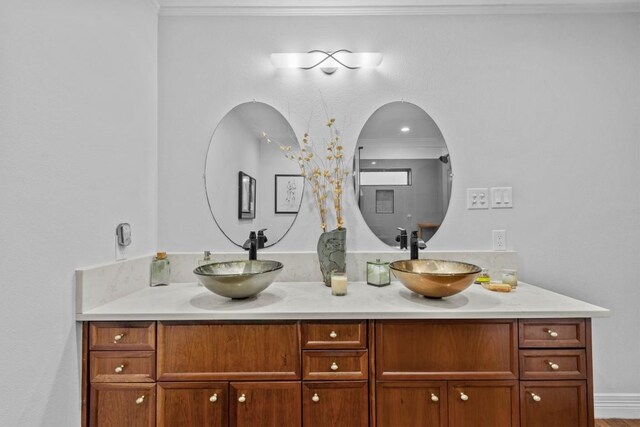 full bath featuring double vanity, a sink, and ornamental molding