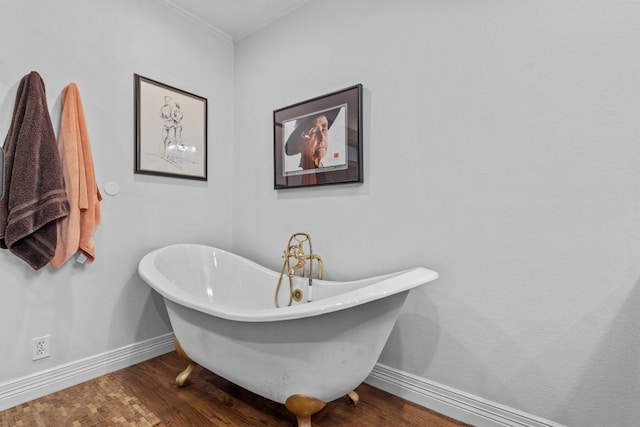 bathroom with crown molding, baseboards, wood finished floors, and a freestanding tub
