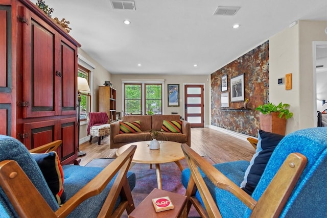 living area with baseboards, visible vents, and wood finished floors