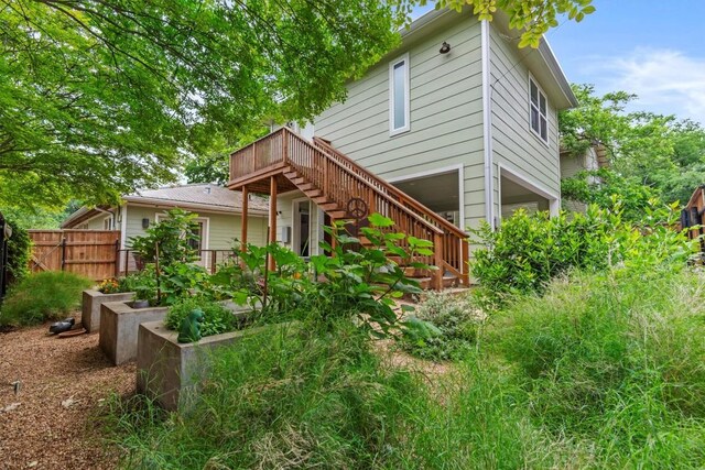 back of property featuring a deck, fence, and stairs