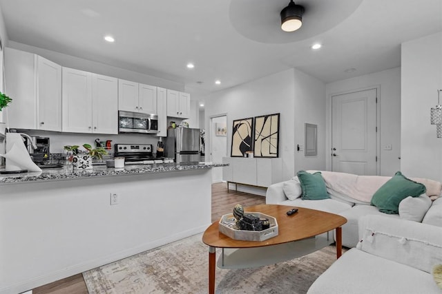 5414 Duval St, Austin, TX 78751 - kitchen with appliances with stainless steel finishes, dark wood-type flooring, a peninsula, white cabinets, and stone countertops