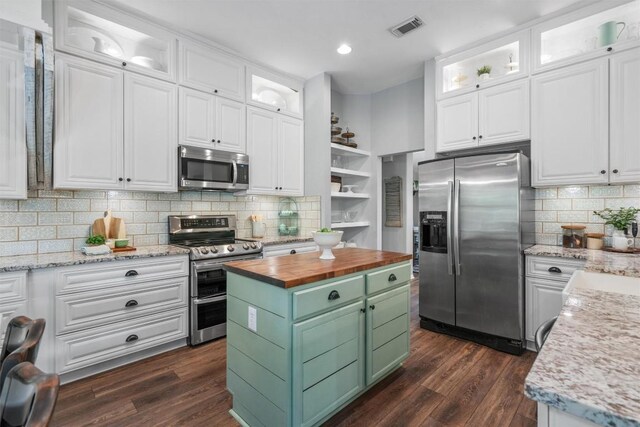 kitchen featuring visible vents, white cabinetry, appliances with stainless steel finishes, and wooden counters
