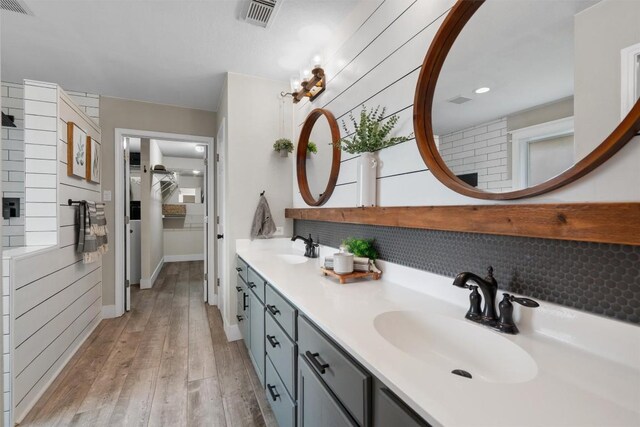 full bath with visible vents, a sink, decorative backsplash, and double vanity