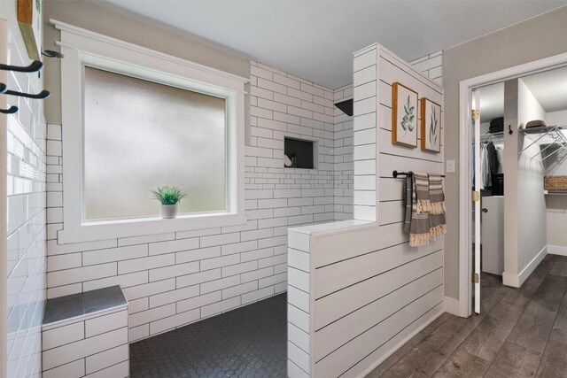 bathroom with baseboards, a walk in shower, a walk in closet, and wood finished floors