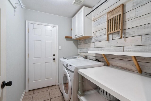 laundry room featuring visible vents, washing machine and dryer, cabinet space, light tile patterned floors, and baseboards