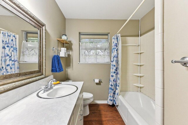 bathroom with shower / tub combo with curtain, vanity, toilet, baseboards, and wood finished floors