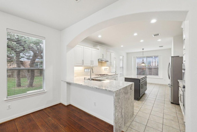 kitchen with light stone countertops, appliances with stainless steel finishes, a sink, tasteful backsplash, and a kitchen island