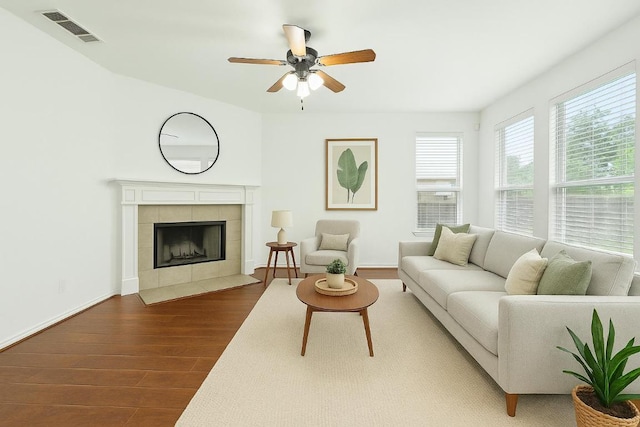 living area with visible vents, ceiling fan, wood finished floors, and a fireplace