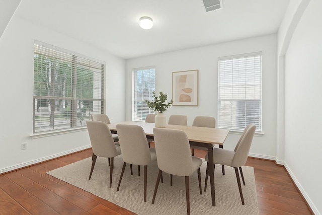 dining space with baseboards, visible vents, and dark wood-style floors