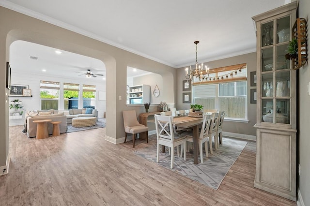dining space with arched walkways, baseboards, wood finished floors, visible vents, and ornamental molding