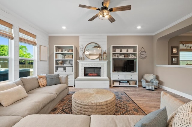 living area with crown molding, ceiling fan, recessed lighting, baseboards, and wood finished floors