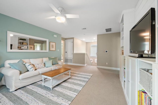 living room featuring visible vents, baseboards, ceiling fan, and light carpet