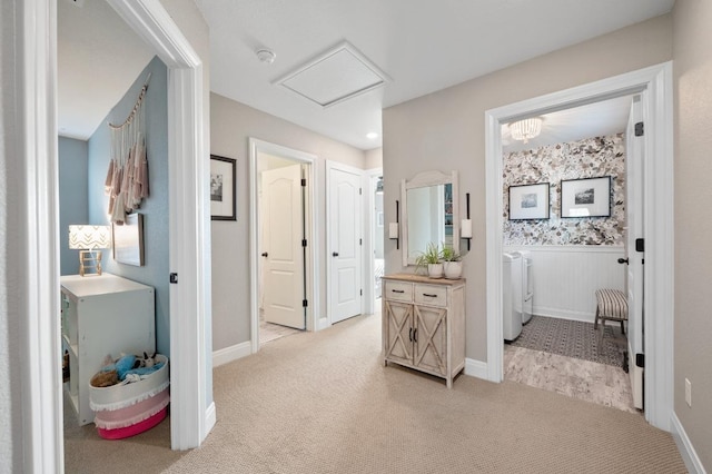 hall featuring attic access, wainscoting, washing machine and dryer, and light carpet