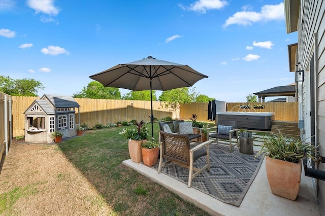 view of yard featuring a hot tub, an outbuilding, a fenced backyard, and a patio area