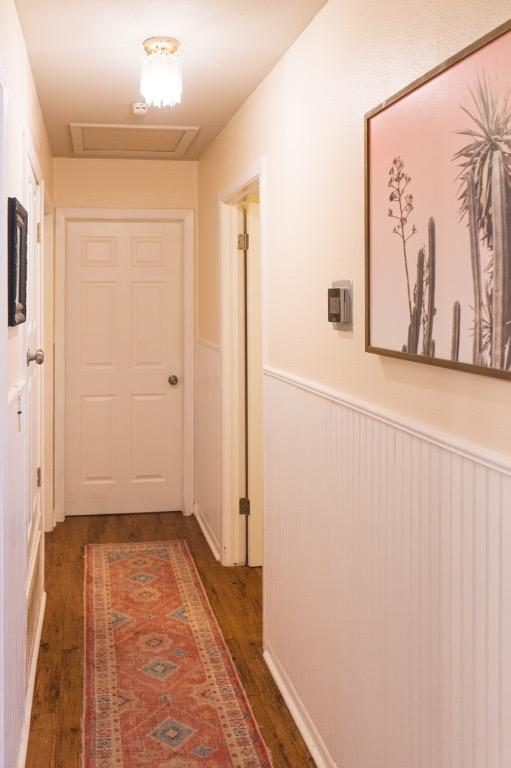 corridor with a wainscoted wall, attic access, and wood finished floors