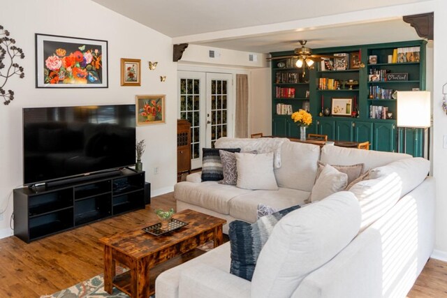living area with french doors, a ceiling fan, baseboards, and wood finished floors