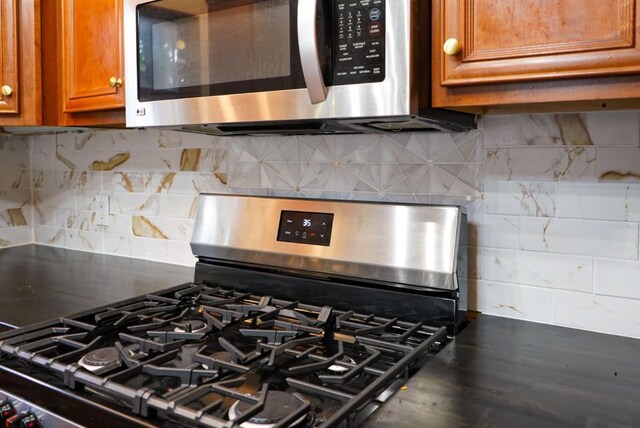 interior details with dark countertops, appliances with stainless steel finishes, decorative backsplash, and brown cabinetry