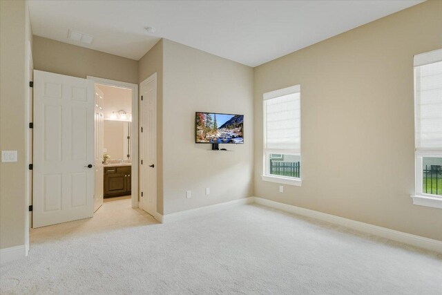 2421 Parisio Ct, Leander, TX 78641 - unfurnished bedroom with connected bathroom, baseboards, and light colored carpet