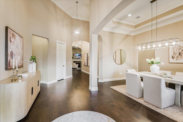 2421 Parisio Ct, Leander, TX 78641 - dining area featuring crown molding, baseboards, a high ceiling, dark wood-type flooring, and arched walkways