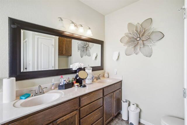 bathroom with double vanity, toilet, and a sink