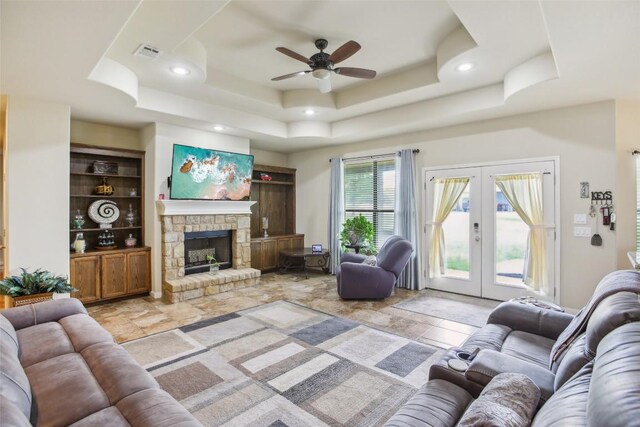 living area with visible vents, stone tile floors, ceiling fan, a raised ceiling, and french doors