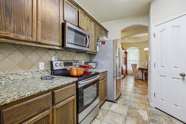 2300 Tumbleweed Trl, Dale, TX 78616 - kitchen featuring appliances with stainless steel finishes, arched walkways, backsplash, and light stone counters
