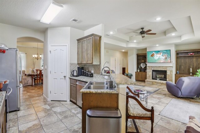 kitchen featuring appliances with stainless steel finishes, a sink, a breakfast bar area, ceiling fan with notable chandelier, and a peninsula