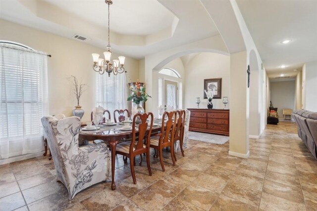 dining room featuring arched walkways, a notable chandelier, a raised ceiling, and visible vents