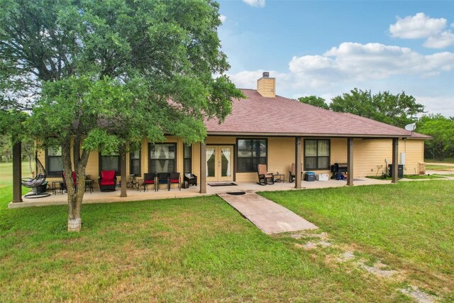 back of property featuring a lawn, a patio area, french doors, and a chimney