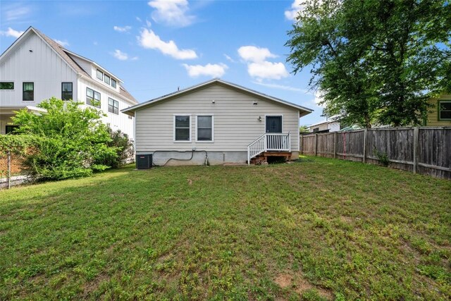 back of property featuring fence, central AC unit, and a lawn