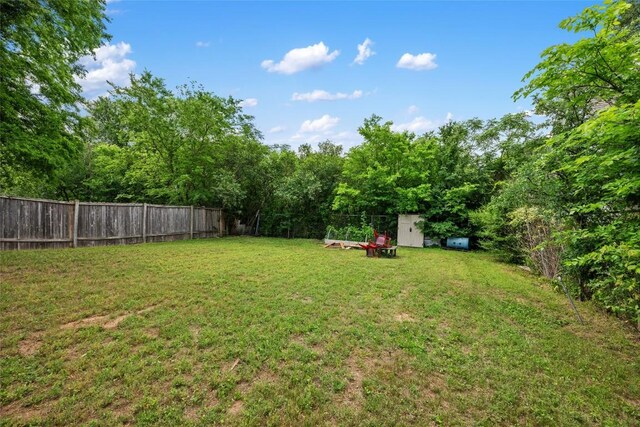 view of yard featuring a fenced backyard, an outbuilding, and a shed
