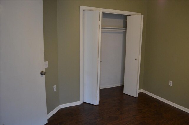 unfurnished bedroom with dark wood-type flooring, baseboards, and a closet