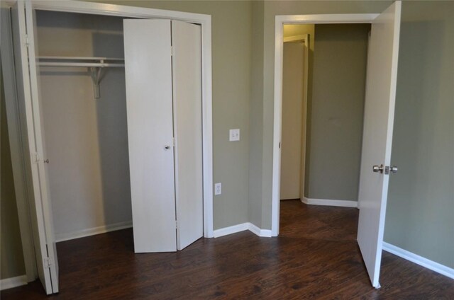 unfurnished bedroom featuring dark wood-style flooring, baseboards, and a closet