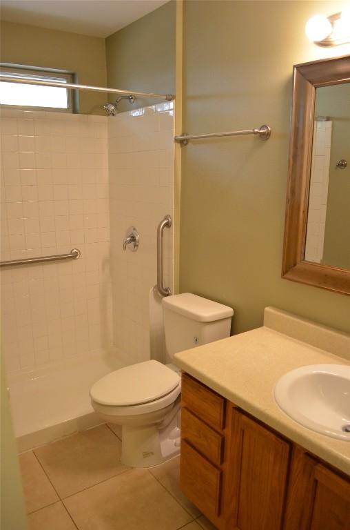 bathroom with vanity, tile patterned flooring, a tile shower, and toilet