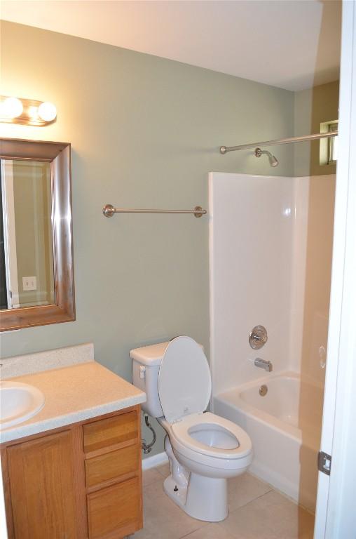 full bath with tile patterned floors, washtub / shower combination, vanity, and toilet