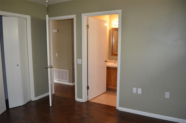 5009 Lott Ave, Austin, TX 78721 - unfurnished bedroom with wood finished floors, baseboards, a closet, ensuite bath, and a sink