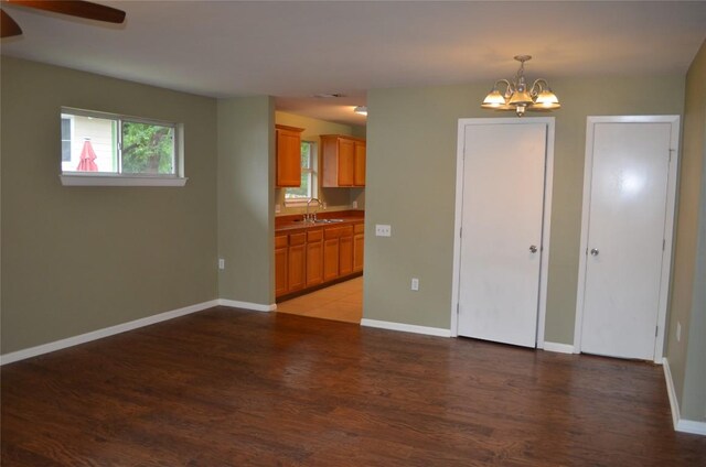 interior space with baseboards, a sink, light wood-style flooring, and ceiling fan with notable chandelier