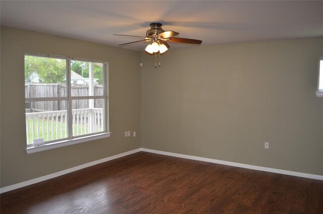 unfurnished room with dark wood-type flooring, a ceiling fan, and baseboards