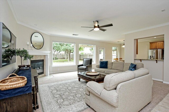 living room with baseboards, ceiling fan, ornamental molding, and light colored carpet