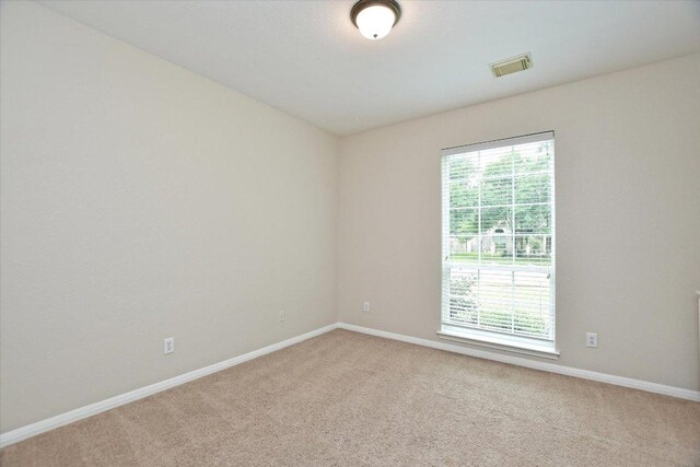 spare room with carpet flooring, baseboards, and visible vents