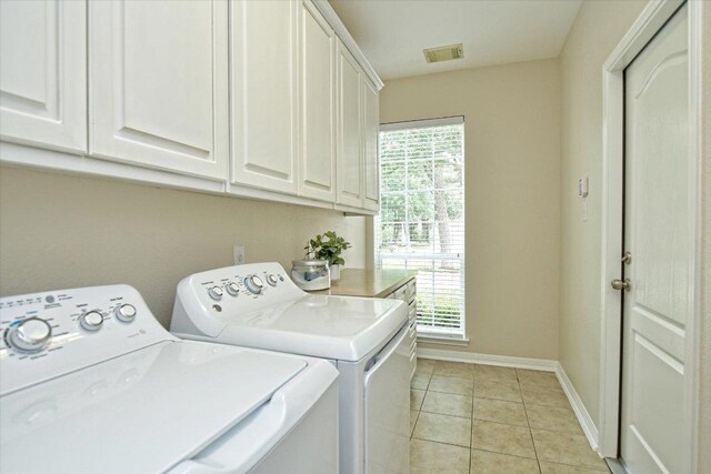 clothes washing area with cabinet space, light tile patterned flooring, visible vents, and washing machine and dryer