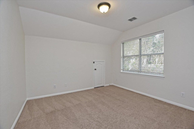 carpeted empty room with baseboards, visible vents, and lofted ceiling